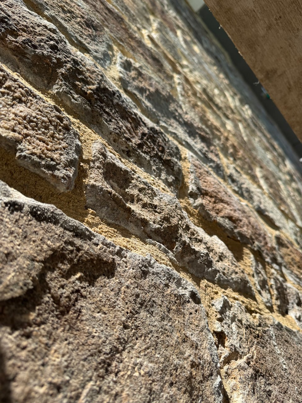 Traditional stone wall undergoing repointing with light-colored lime mortar in Cornwall.